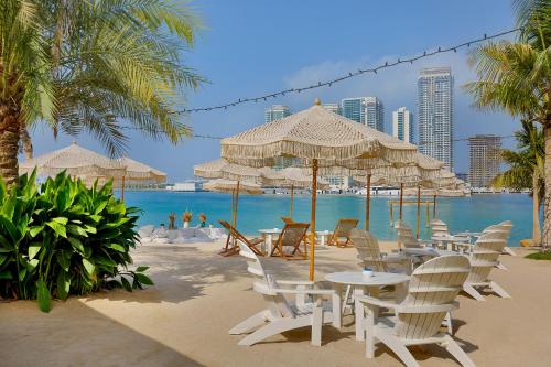 a beach with tables and chairs and the ocean at W Dubai - Mina Seyahi, Adults Only in Dubai