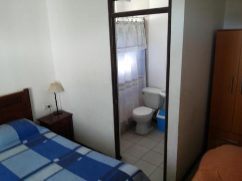 a bedroom with a bed and a bathroom with a toilet at Residencial Las Palmeras in Iquique