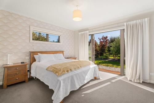 a bedroom with a bed and a large window at Cedar Sanctuary - Albert Town Holiday Home in Wanaka