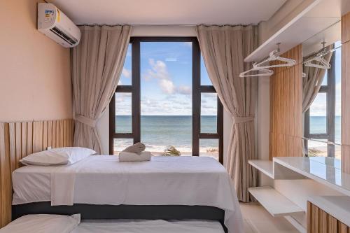 um quarto com uma cama e vista para o oceano em Varandas do Mar Condomínio Moderno por Carpediem em Caucaia