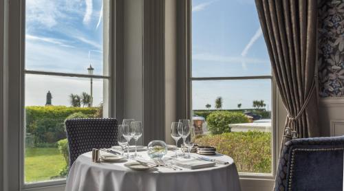 a table with wine glasses in a room with a window at The Grand Hotel in Eastbourne