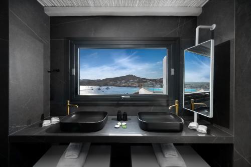 a bathroom with a sink and a large window at Deliades Hotel in Ornos