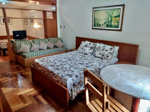 Dublin Hotel في ساو باولو: غرفة نوم بسرير واريكة وطاولة
