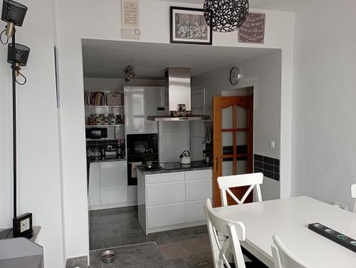 una cocina con armarios blancos y una mesa con sillas. en Casa Rural Olivares en Villanueva de Algaidas