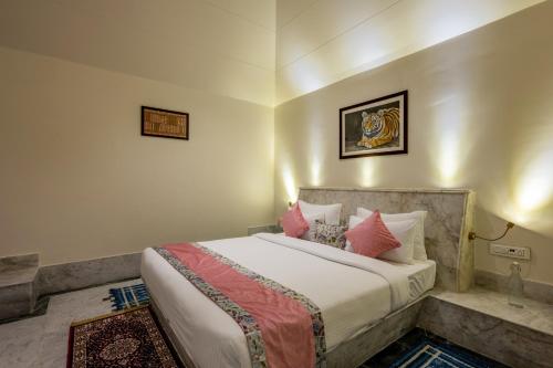 1 dormitorio con 1 cama grande con almohadas rosas en Aangan Resort Ranthambhore - A Private Pool Villa, en Khilchīpur