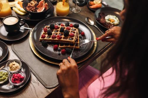 a woman eating a plate of waffles and berries on a table at Alpenhotel Kitzbühel am Schwarzsee - 4 Sterne Superior in Kitzbühel