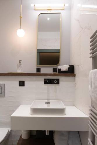 une salle de bain blanche avec un lavabo et un miroir dans l'établissement Hotel de la Poste, à Corps