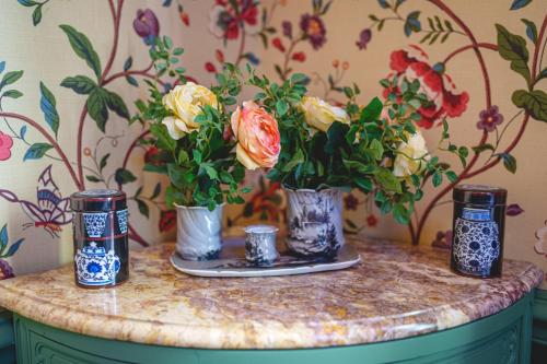 a table with three vases with flowers on it at Château La Comtesse de Loire & Spa in Saumur