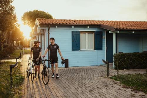 two people walking their bikes in front of a house at Natural Village Resort in Porto Potenza Picena