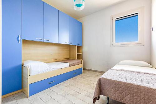 una camera con due letti, armadi blu e una finestra di DORMIGLIONE APARTMENT a Torre Lapillo