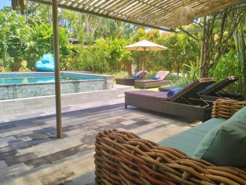 a patio with chairs and an umbrella and a pool at Villa Jeruk in Selong Belanak