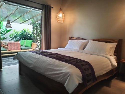 a bedroom with a large bed and a large window at Villa Jeruk in Selong Belanak