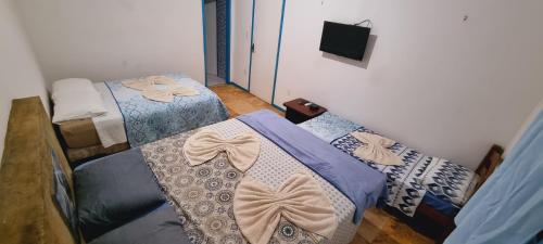 a bedroom with two beds and a tv on the wall at Casa do Galego no Residência Família in Canoa Quebrada