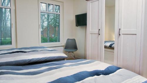 1 dormitorio con 2 camas, silla y ventanas en Quartier2, en Zeven