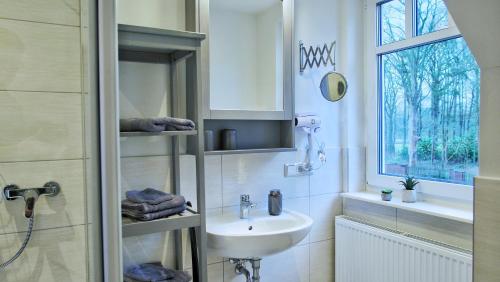 a white bathroom with a sink and a window at Quartier3 in Zeven