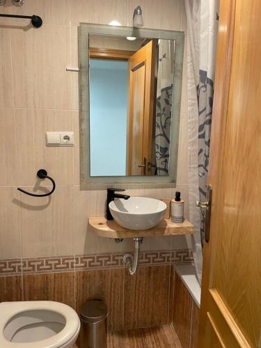 a bathroom with a sink and a toilet and a mirror at Traveler's Beach Apartment with sea view, free coffee & parking in Benidorm