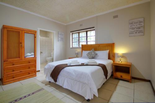 a bedroom with a large bed and a bathroom at Eagles Nest Guesthouse in Eshowe