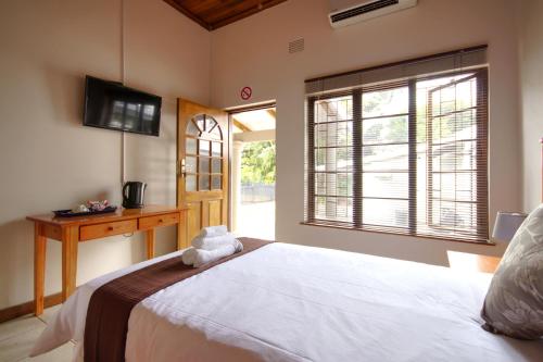 a bedroom with a large white bed and a window at Eagles Nest Guesthouse in Eshowe