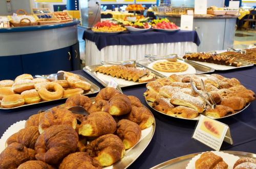 a table filled with different types of pastries on plates at Hotel Luna in Bibione