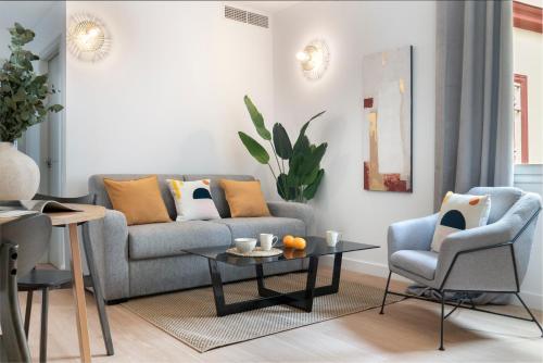 ein Wohnzimmer mit einem Sofa, einem Tisch und Stühlen in der Unterkunft Suites Maestranza - Santas Patronas by Magno Apartments in Sevilla