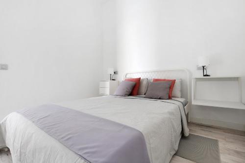 a white bedroom with a large white bed with red pillows at La Corte A1 in Antigua