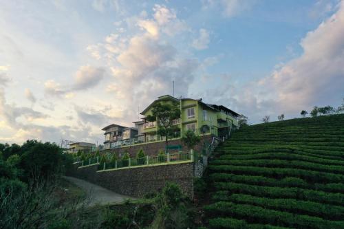 a house on top of a hill next to a field at Vaga Mist Resort Vagamon in Idukki