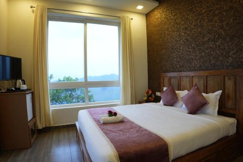a bedroom with a large bed with a large window at Vaga Mist Resort Vagamon in Idukki