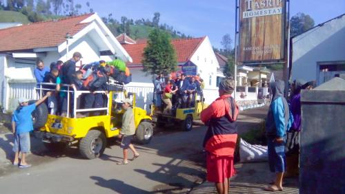 a group of people standing around a yellow truck at Pak Tasrip Homestay in Bromo