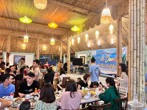 a group of people sitting at tables in a restaurant at Minh Chau Beach Resort in Quang Ninh