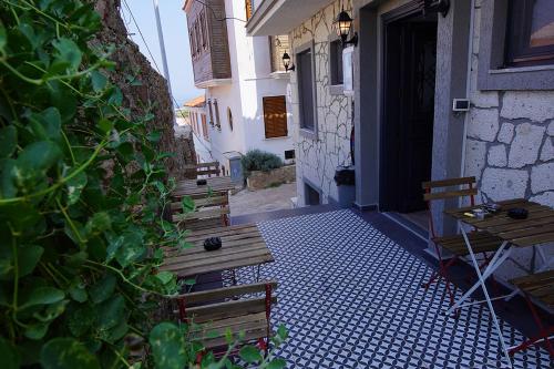 a patio with benches and a table and a building at ACHİLLES BOZCAADA in Bozcaada