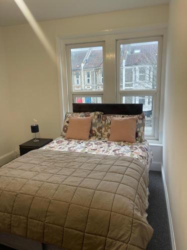 a bedroom with a large bed with two windows at Lovely room in Bristol 5 in Bristol