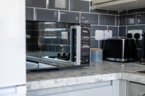 a microwave oven sitting on top of a kitchen counter at Elmcroft Apartment - 10 Mins Walk to Woking Town Centre in Woking