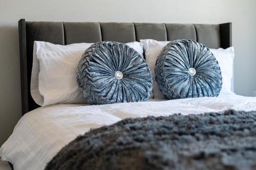 Una cama con dos almohadas azules. en Elmcroft Apartment - 10 Mins Walk to Woking Town Centre, en Woking