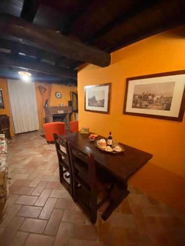 comedor con mesa de madera y paredes de color naranja en Il borgo di Firenzuola Camere con camino en Crocemaroggia