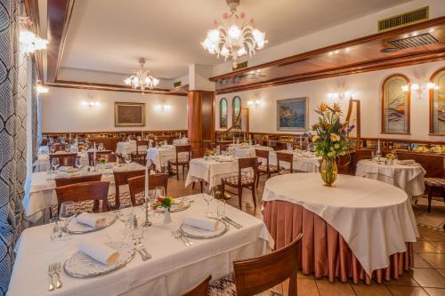 uma sala de jantar com mesas e cadeiras brancas em Hotel Marko em Portorož