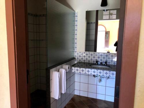 W łazience znajduje się umywalka i lustro. w obiekcie Pousada Condado Santa Maria w mieście Baependi