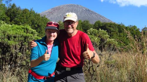a man and woman giving thumbs up in front of a mountain at Pak Tasrip Homestay in Bromo