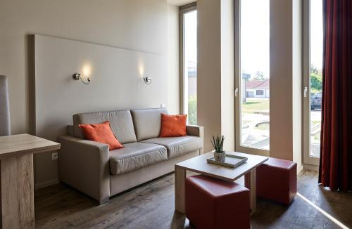 a living room with a couch and a table at Holiday Suites Westende - Middelkerke in Middelkerke