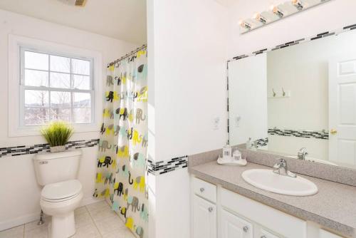 La salle de bains est pourvue de toilettes, d'un lavabo et d'un miroir. dans l'établissement Fun & Fabulous Getaway, à Gilford