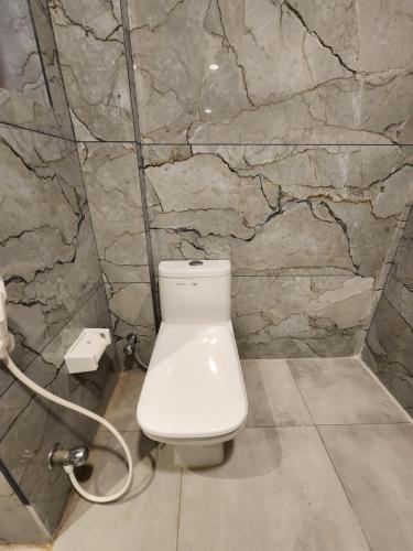 a white toilet in a bathroom with a stone wall at Square9 - A Boutique Hotel in Gurgaon