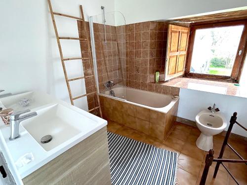 a bathroom with a sink and a tub and a toilet at Cottage de Keran in Arradon