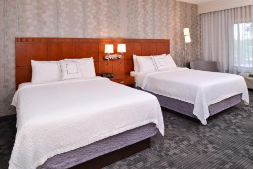 um quarto de hotel com duas camas com lençóis brancos em Courtyard Pittsburgh Monroeville em Monroeville