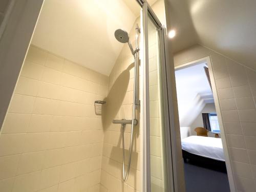 een badkamer met een inloopdouche naast een bed bij Villa Vindina in De Panne