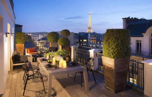 un balcon avec tables et chaises et vue sur la tour Eiffel dans l'établissement Hotel Marignan Champs-Elysées, à Paris