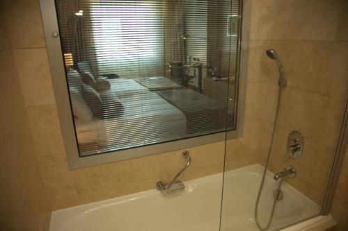 a bathroom with a shower and a tub with a glass door at CPAnkara Hotel in Ankara