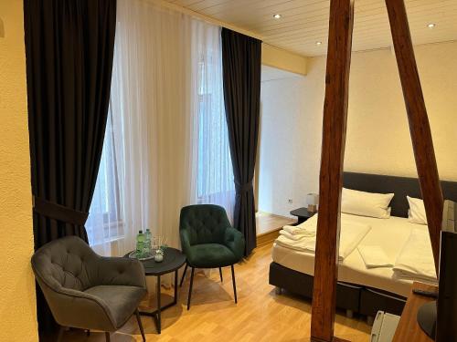 a bedroom with a bed and two chairs and a table at Hotel-Café-Burg Stahleck in Bacharach