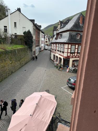 a pink umbrella on a street with buildings at Hotel-Café-Burg Stahleck in Bacharach
