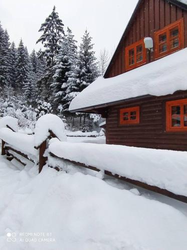 a snow covered bench in front of a cabin at Chata U Juraja in Hruštín