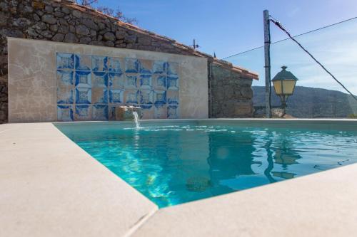 a swimming pool with a fountain in front of a building at El Escondite del Agua in Trevejo