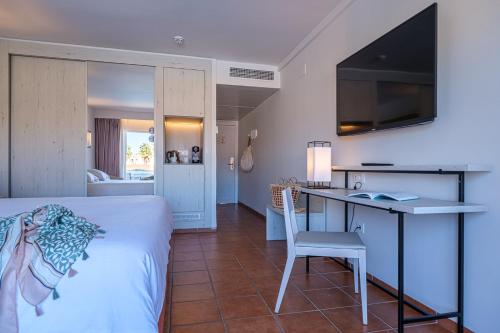 a bedroom with a bed and a table and a desk at Oassium Hotel - Adults Only in La Pineda